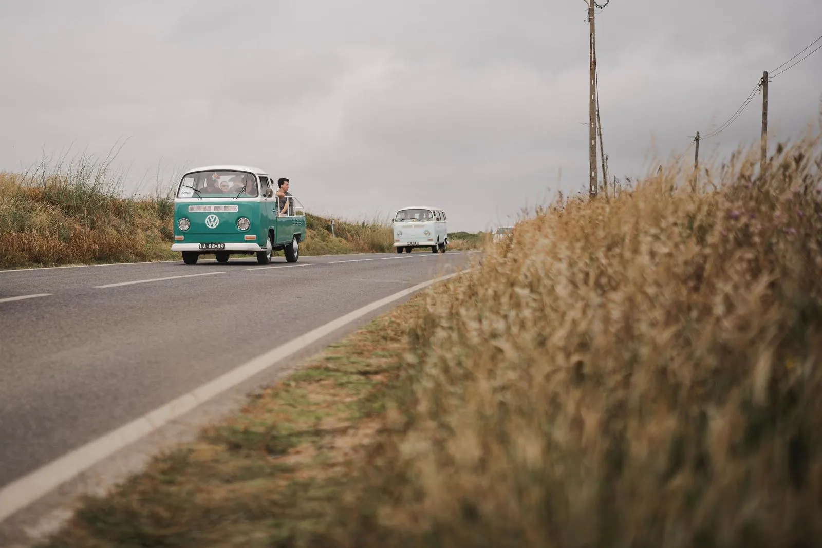 Two vintage camper vans on a country road between fields.